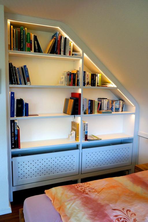 Dachschrägen-Bücherregal in weiß mit LED-Beleuchtung und Heizkörperverkleidung