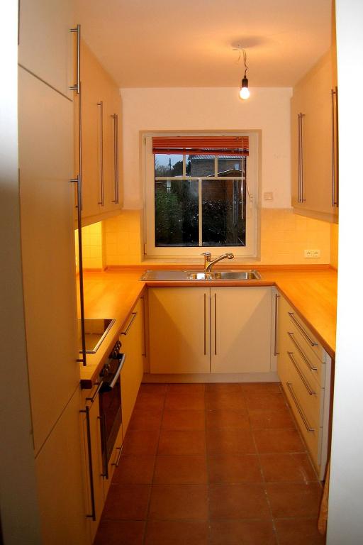 Schmale Einbauküche mit viel Arbeitsfläche und weißen Fronten