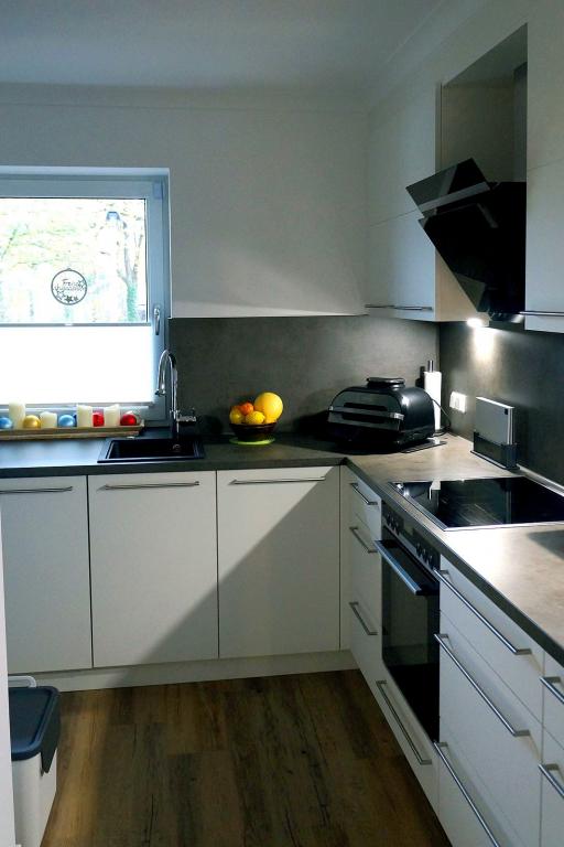Weiße Einbauküche mit Induktions-Kochfeld, Ofen und dunkler Arbeitsplatte