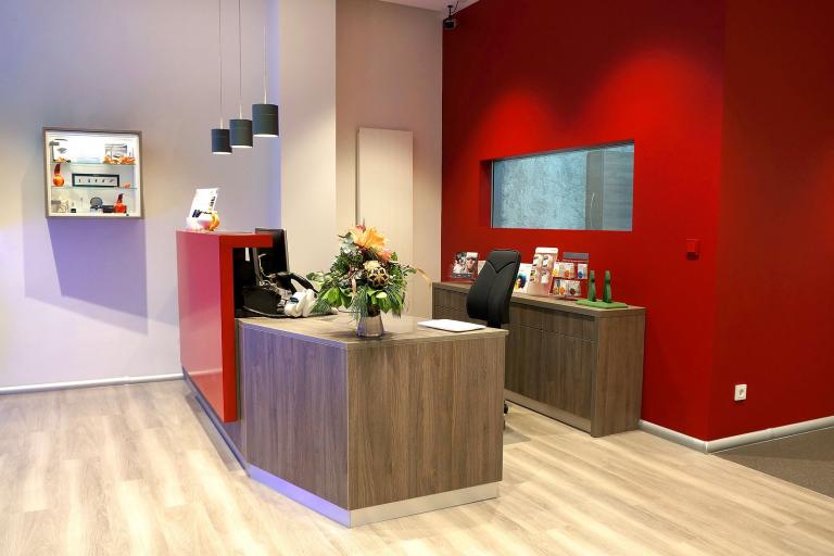 Empfangsbereich mit Tresen, Ausstellungskasten, Schreibtisch und Aktenschränken